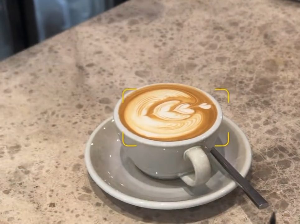 A finished latte set on FAVE’s stone counter, from the rush hour video carousel