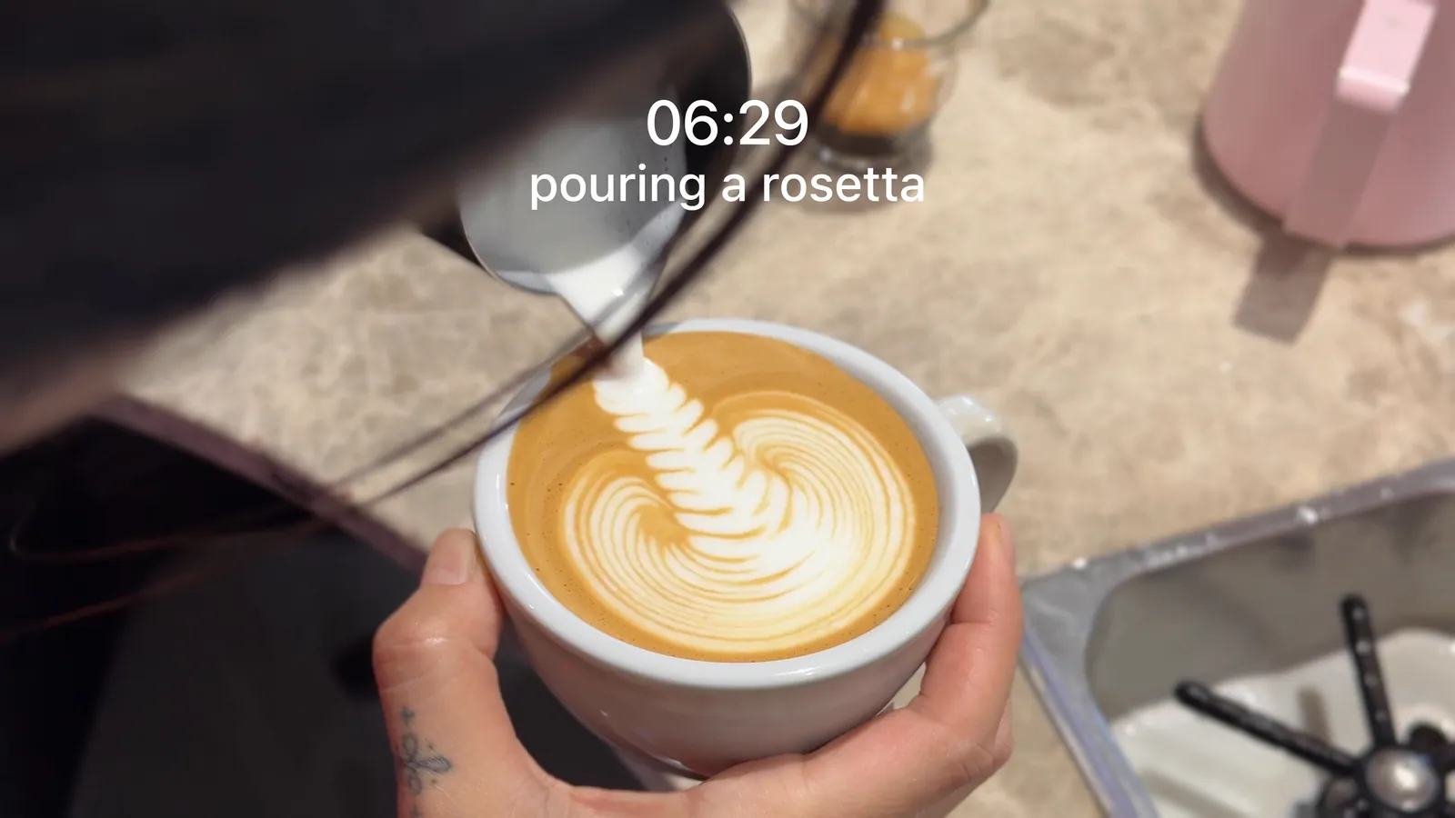 The same frame of the rosetta pour with the text as posted: 06:29 above pouring a rosetta, in plain white with no outline or shadow.