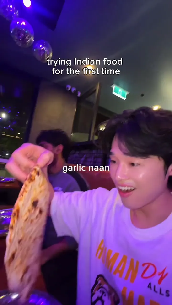 MJ holds up garlic naan at Indian Room, then tries the butter chicken.